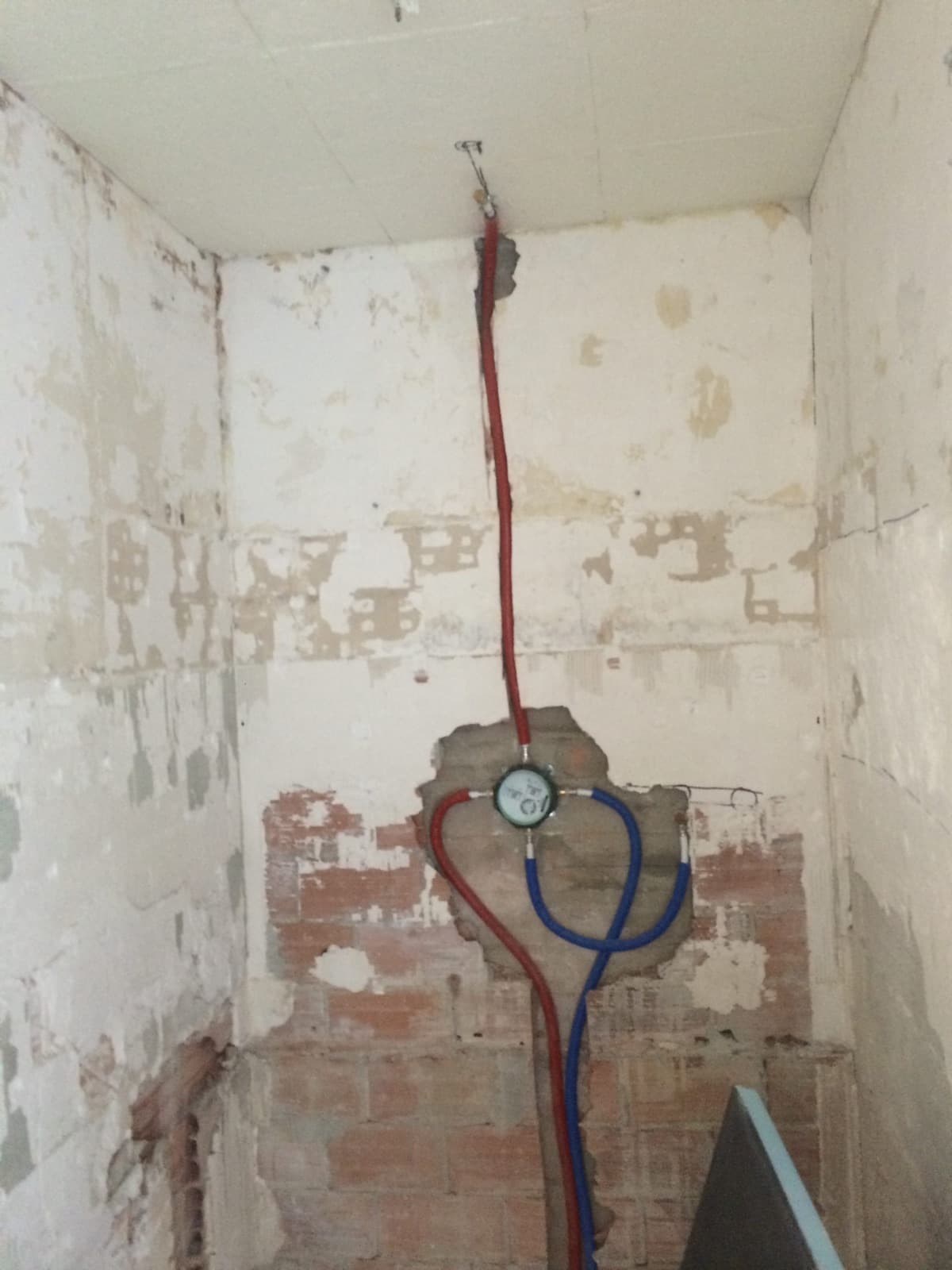 Arrivées d’eau chaude et d’eau froide en tube PER rouge et bleu dans un mur en rénovation